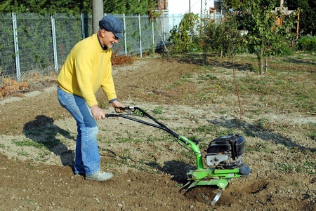 Middle age man with a rototiller in the gardenの写真素材