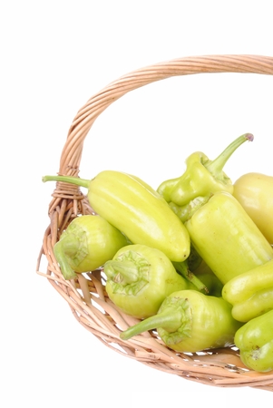 green peppers in a straw basket, isolated on whiteの写真素材