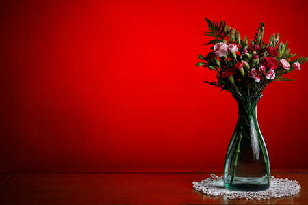 Concept love, valentine's day, passion. Copy space. Image of a green vase with roses and blossoms. Red background.の写真素材