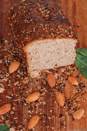 Top view of whole wheat bread on a rustic wooden background with mixed seeds, almonds and mint leaves.の写真素材