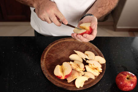 Close-up detail shot of Caucasian man's hands cutting apples into pieces. Top view. Series of...