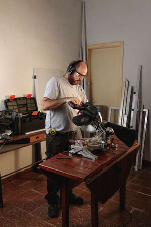 A Top view of man working in a carpentry shop. Assembling a white aluminum window. Horizontal image.