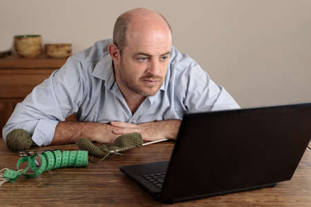 A Worker looking at camera. He is in a carpentry shop and has safety accessories on. He grabs an electric machine to cutの写真素材