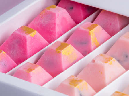 Close up of fine pink and gold chocolates in a white box.