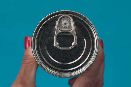 A Woman's hand holding a can of food and another hand pointing to the can. Isolated elements on pink background.の写真素材