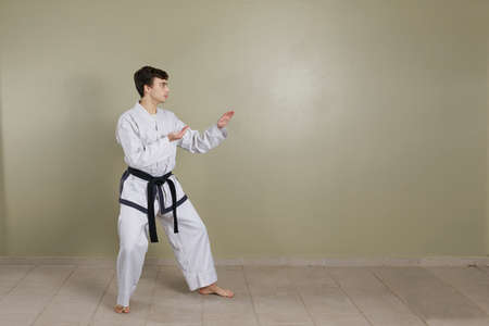 A Young Caucasian man putting on a taekwondo combat shin guard on his leg. Sportswear.の写真素材