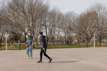 A young adults or teenagers, Hispanic American Latino men and women, playing basketball on a park...