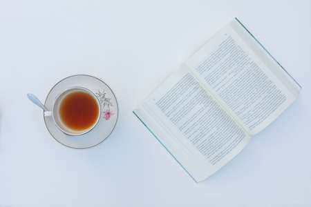 Top view. Tea cup and book on white table in background. Copy space for text. Concept benefits of reading.の写真素材