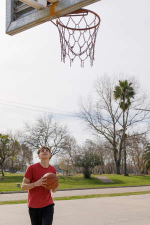 young athlete on the basketball court in a public park. He has the ball and looks at the basket...