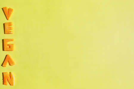 A Vegan word made with orange pumpkin letters. Yellow background. Copy space.の写真素材