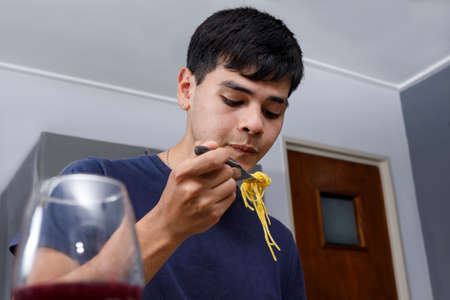 Latin man eating Italian pasta. Look serious about food.の写真素材
