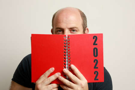 close up of adult Caucasian male holding a red agenda of the year 2022の写真素材