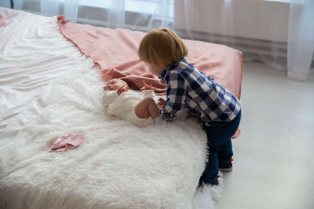 a little boy with his younger sister on the bedの写真素材