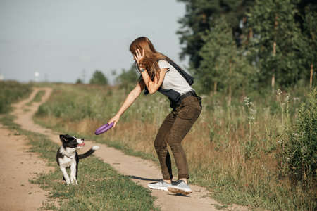 Girl playing with black and white border collie dog puppy on the forest pathの写真素材