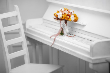 orange orchid bouquet on white pianoの写真素材