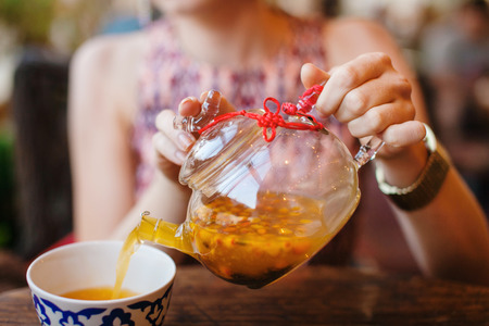 Female Hnds Pouring Sea Buckthorn Tea in Glass Kettleの写真素材