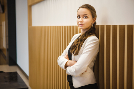 Dark-haired girl standing at wall with crossed armsの写真素材