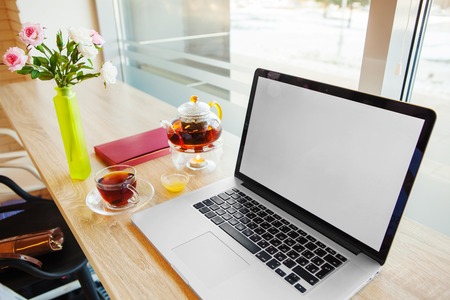 Open notebook, hot tea, table-book and vase with roses stands on tableの写真素材