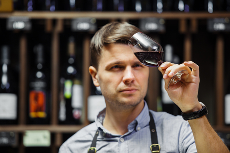 Bokal of red wine on background, male sommelier appreciating drinkの写真素材