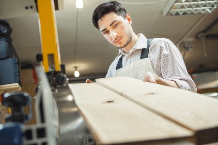 Young worker holding and looking at two plankingsの写真素材