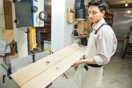 Young worker holding and looking at two plankingsの写真素材