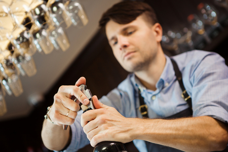 Male sommelier open wine bottle with corkscrew.の写真素材