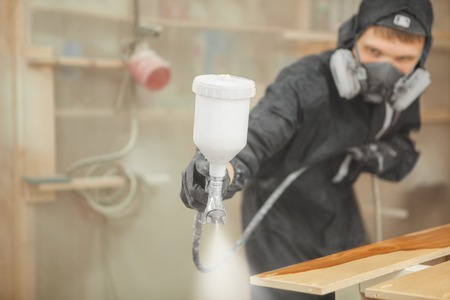 Man in respirator mask painting wooden planks at workshop.の写真素材
