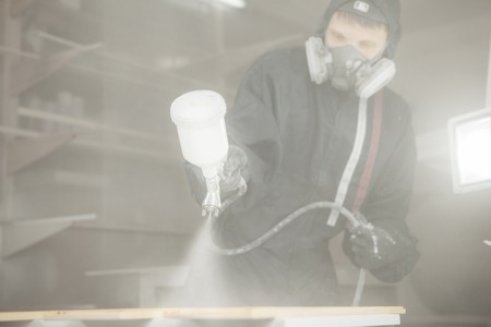 Man in respirator mask painting wooden planks at workshop.の写真素材