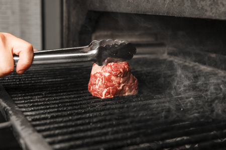 Fresh meat on hot grilled cook with lattice closeup view. Steak preparing on cooker, juicy roasted beef with proteins in cooker stoveの写真素材