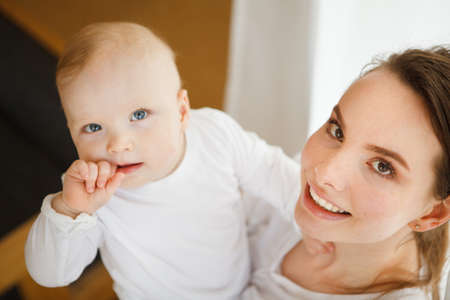 Mother hugs baby toddler smelling his tasty body, happy moments together with little child, mom and...