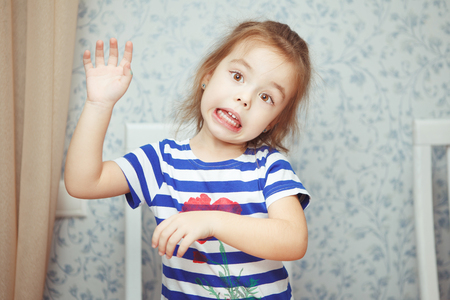 Cute little girl in striped T-shirt makes funny faceの写真素材