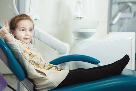 Little child sits in comfortable leather dentist chairの写真素材