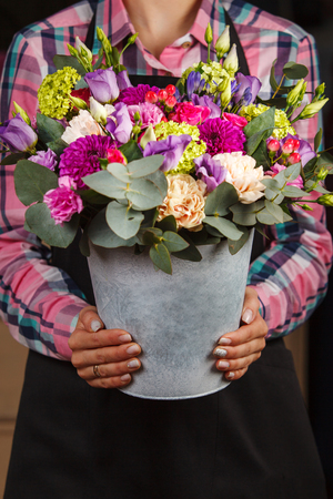 female hands holding a floral bouquet in a bucketの写真素材