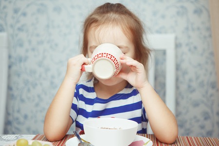 Little girl has her morning breakfast and drinks teaの写真素材
