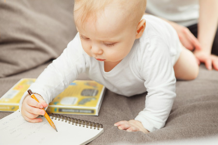 Concentrated young toddler learning draw. Baby hold pencil in handの写真素材