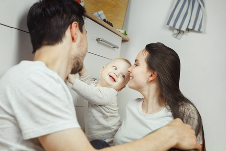 Smiling infant stands holding hand on chest of drawersの写真素材