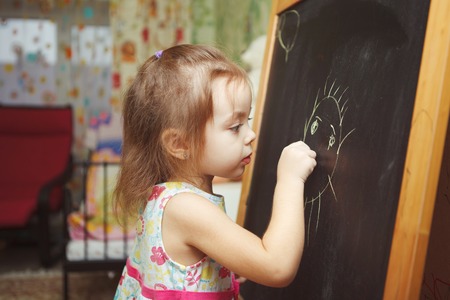 Girl with ponytail in process of drawing picture of sunの写真素材