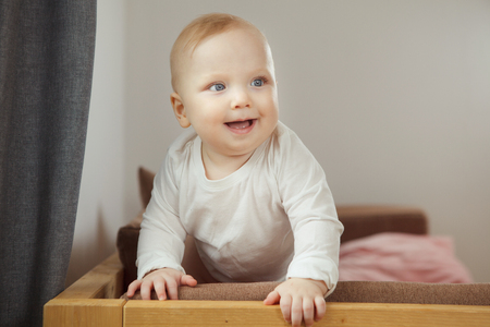 Smiling baby standing at the sofa relying on support.の写真素材