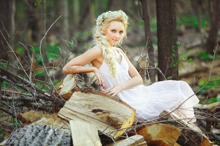 beautiful woman sits in forest on chopped stumps.の写真素材