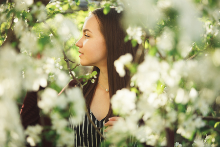 young woman with clean skin near a blooming apple tree. portrait of girl in spring park.の写真素材