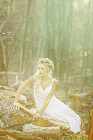 beautiful woman sits in forest on chopped stumps.の写真素材