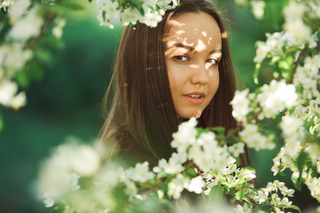 young woman with clean skin near a blooming apple tree. gentle portrait of girl in spring park.の写真素材