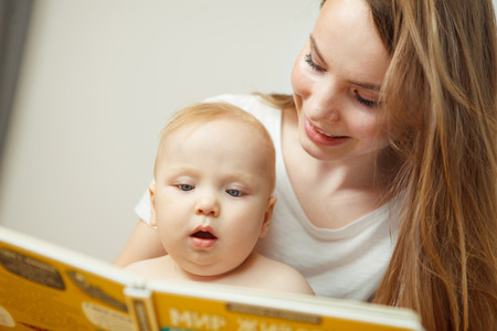 Mother reading to little infant colorful book with fairy tales.の写真素材