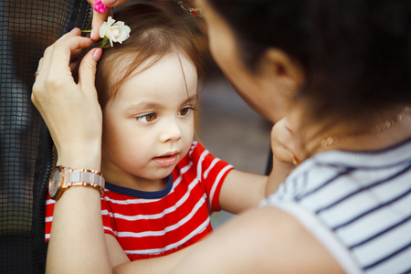 mother decorates her daughters hair with white rose flower.の写真素材