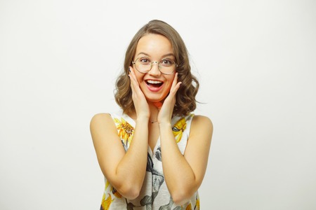 Surprised woman with pleasant emotions puts his hands on cheeks, expressing surprise and unpredictability of expectations.の写真素材