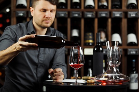 Sommelier pouring red wine from bottle in glassの写真素材