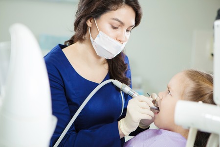 Child feels toothache during polishing procedure in dentist chairの写真素材