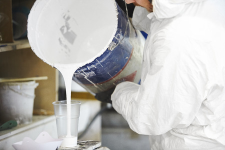 Man pours dosed amount of paint in a plastic cup.