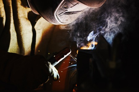 Close-up image of industrial worker at the factory welding steel structure on black background.の写真素材