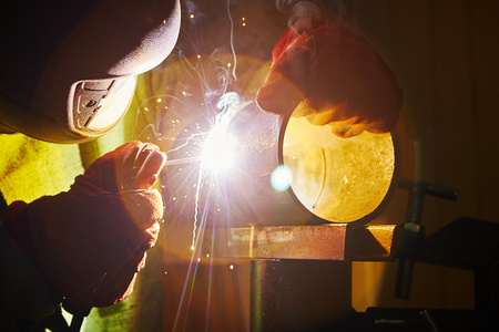 Male in face mask welds with welding